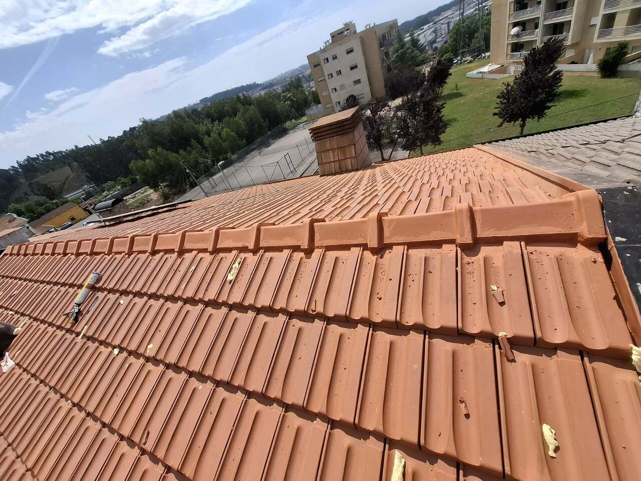 Detalhe de acabamento em telha cerâmica nova, com vista da cidade