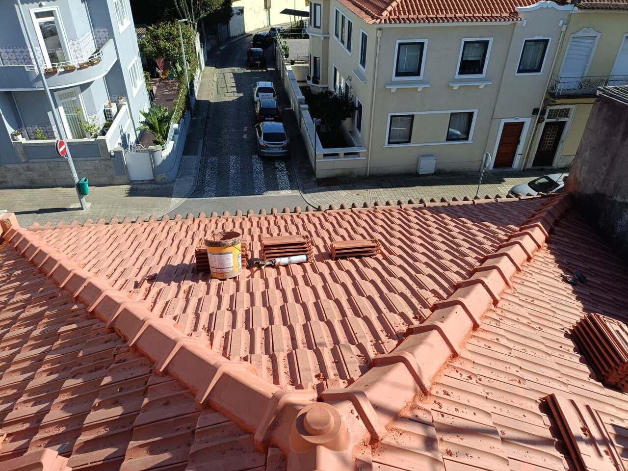 Telhado novo em telha cerâmica com cumeeira acabada, vista sobre a rua